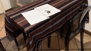 A dining table with a striped tablecloth, a chair, and a document on the table. - 1 bedroom apartment in rome (Roma)