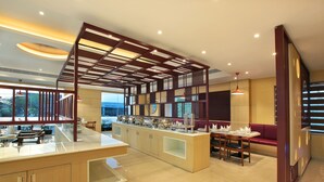 Un moderno hall de hotel con zona de buffet, asientos y vistas al exterior.