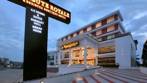 Un hotel llamado "Tribute Royale" con un diseño arquitectónico moderno, que presenta una entrada destacada y una fachada bien iluminada.