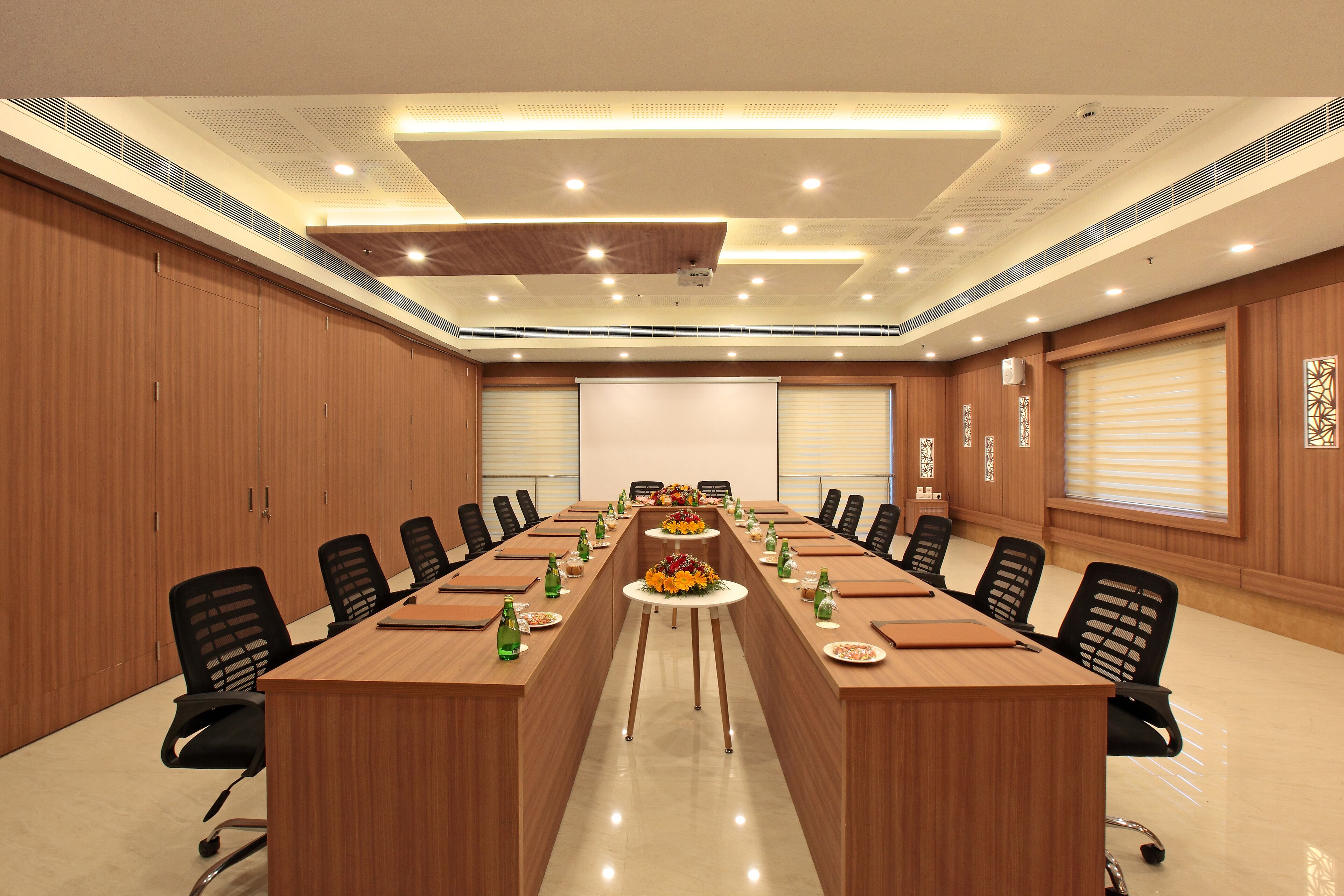 A conference room with a long table, chairs, and a projector screen.