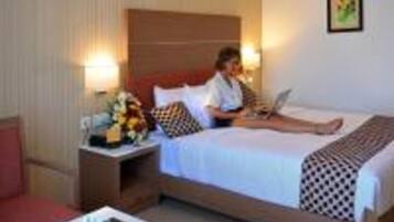 A hotel room with a bed, a desk, a nightstand, and a lamp.