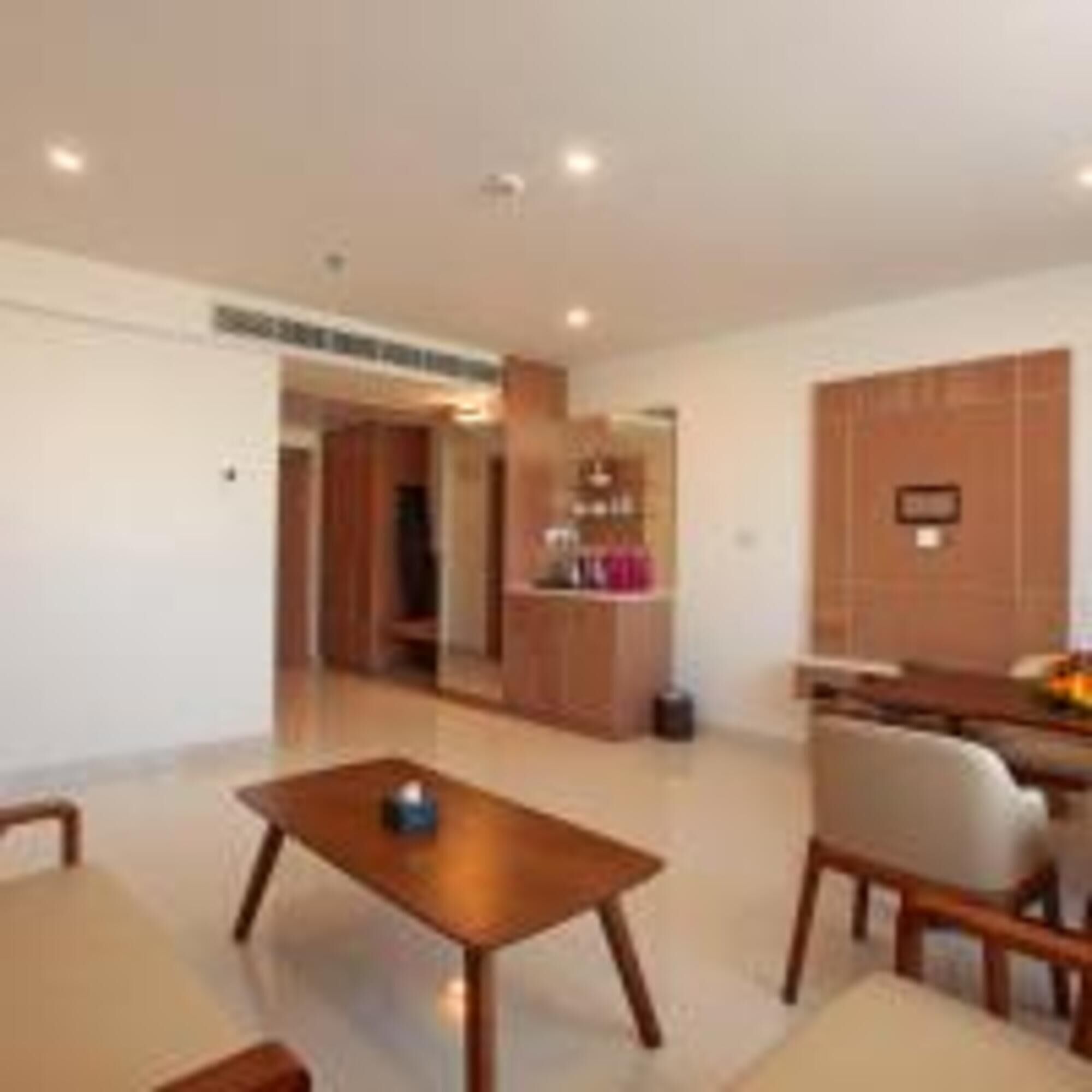 A modern living room with a wooden coffee table, a sofa, and a dining area with a table and chairs.