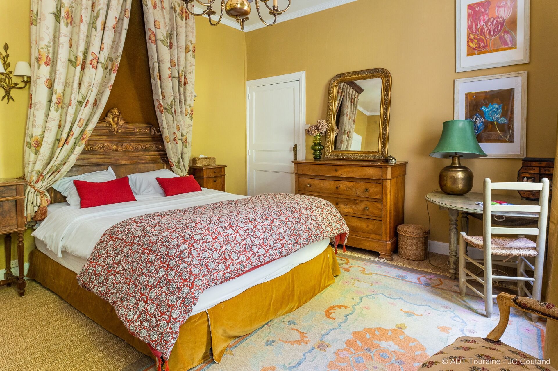 Quarto com cama, penteadeira, cadeira, abajur e espelho.