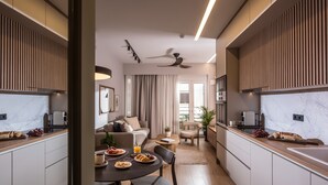 Eine moderne Küche mit Essbereich, ausgestattet mit einer Marmorarbeitsplatte, Holzschränken und einem Deckenventilator.