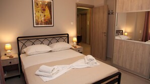 A neatly made bed with white linens and towels, a painting above it, and a wooden wardrobe to the right. - Ariadni s Athenian Apartment (Athens)