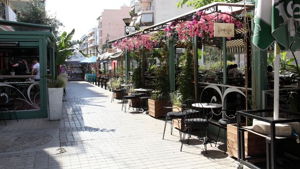 An outdoor café with tables and chairs, surrounded by buildings and greenery. - Ariadni s Athenian Apartment (Athens)