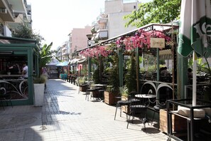 An outdoor café with tables and chairs, surrounded by buildings and greenery. - Ariadni s Athenian Apartment (Athens)