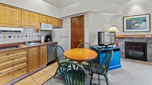 A compact kitchen with wooden cabinets, a microwave, a sink, and a dining table with chairs.