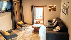 A modern living room with a grey sofa, a grey armchair, and a wooden coffee table. - Appartement Chez Léon Avec Jardin (Samoëns)