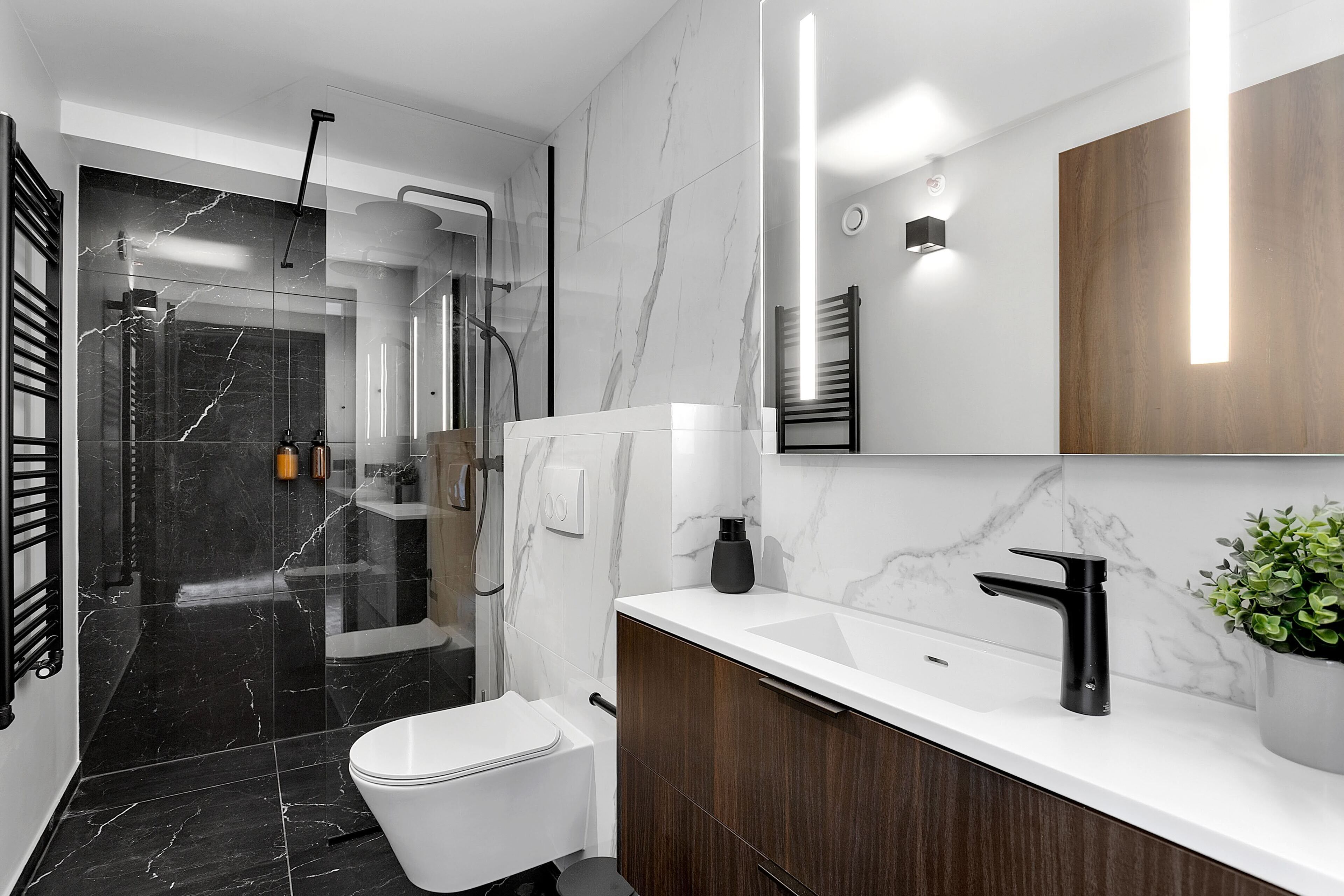 A modern bathroom with a white toilet, a black sink, and a shower area.
