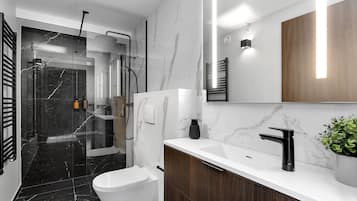A modern bathroom with a white toilet, a black sink, and a shower area.