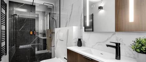 Un baño moderno con inodoro blanco, lavamanos negro y zona de ducha.