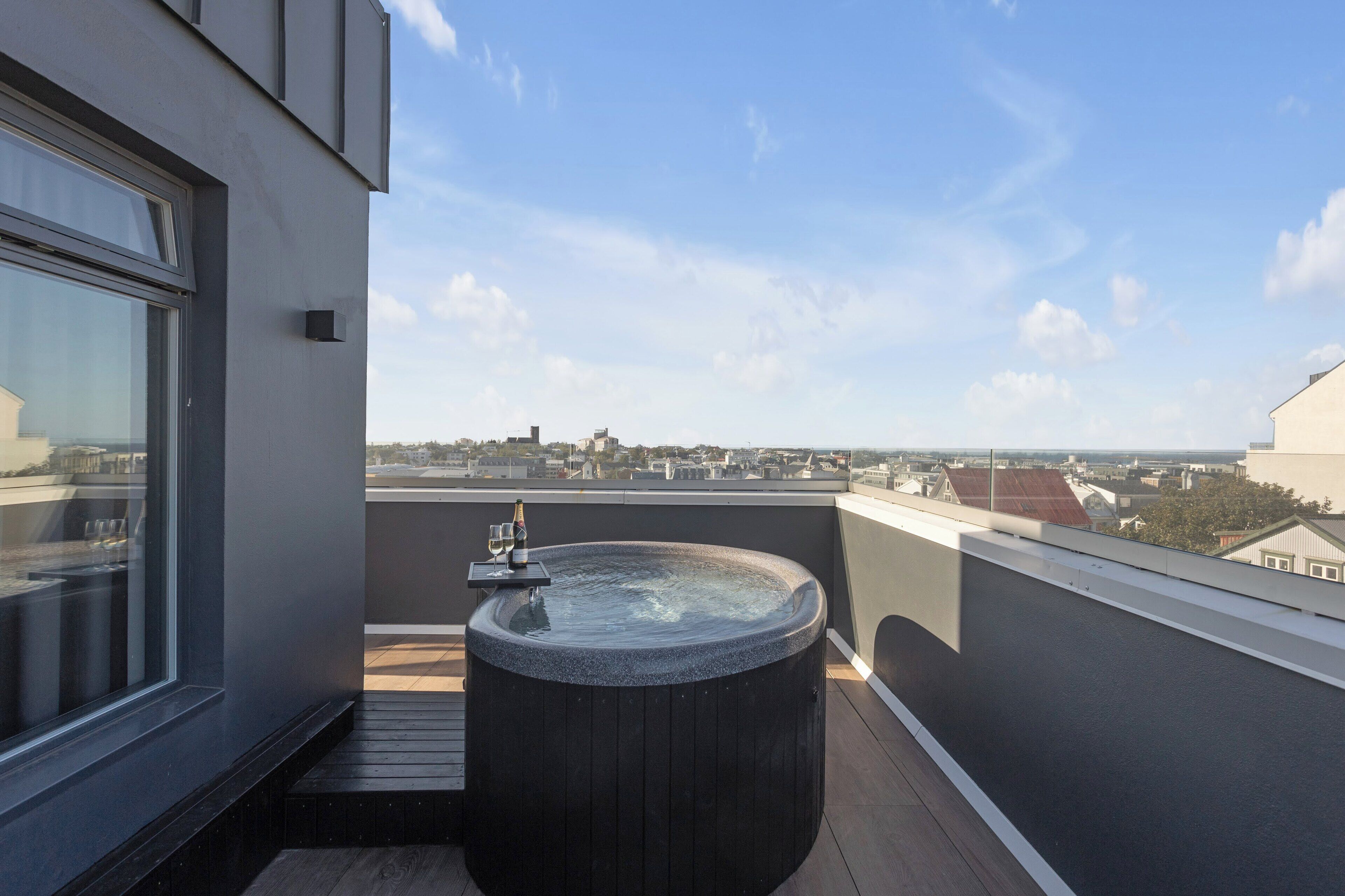 A hot tub on a balcony with a city view.