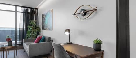 A modern office space with a desk, chair, sofa, and a large window with curtains.