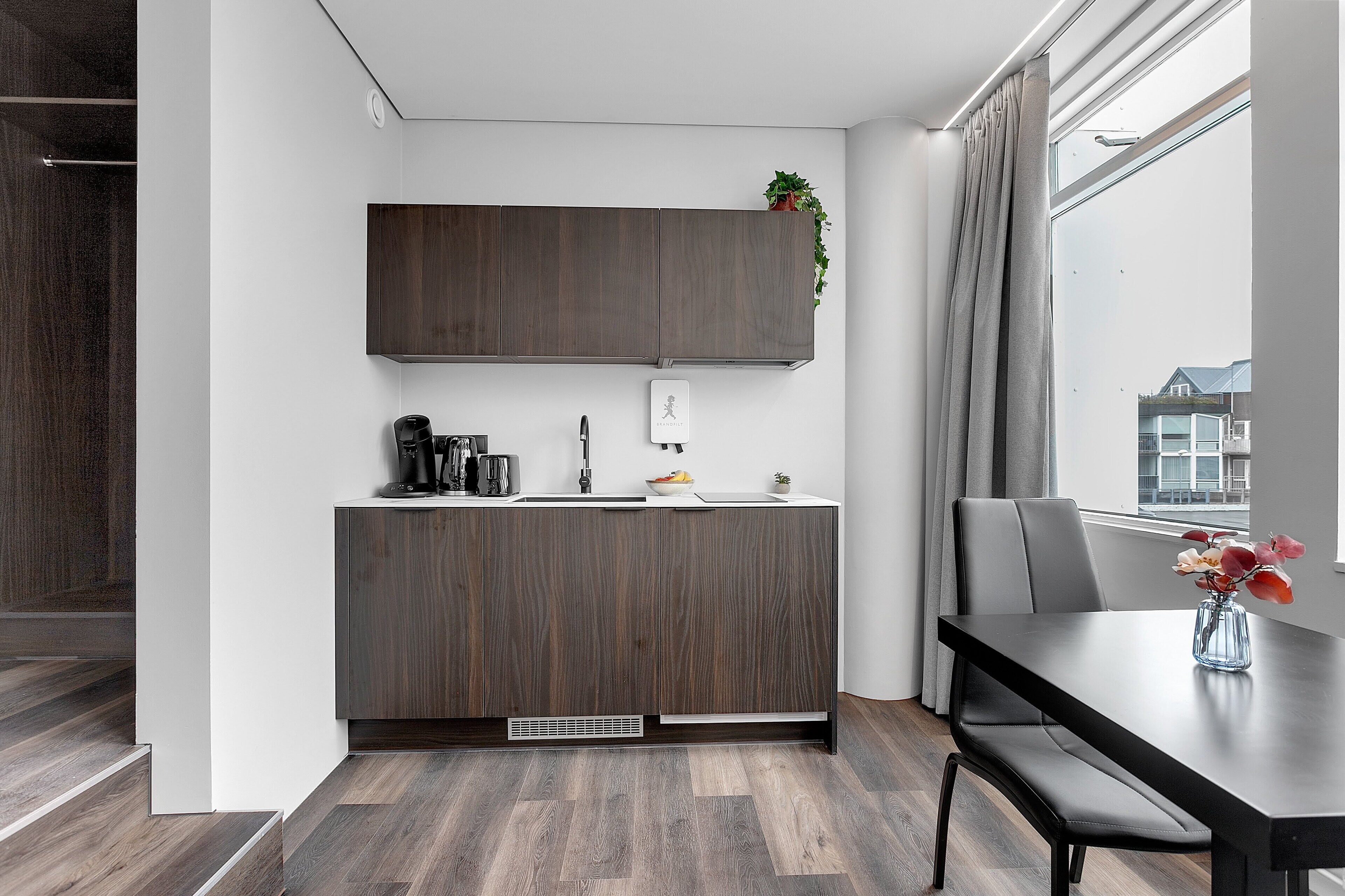 A modern kitchen with dark wood cabinets, a built-in sink, and a dining area with a table and chairs.