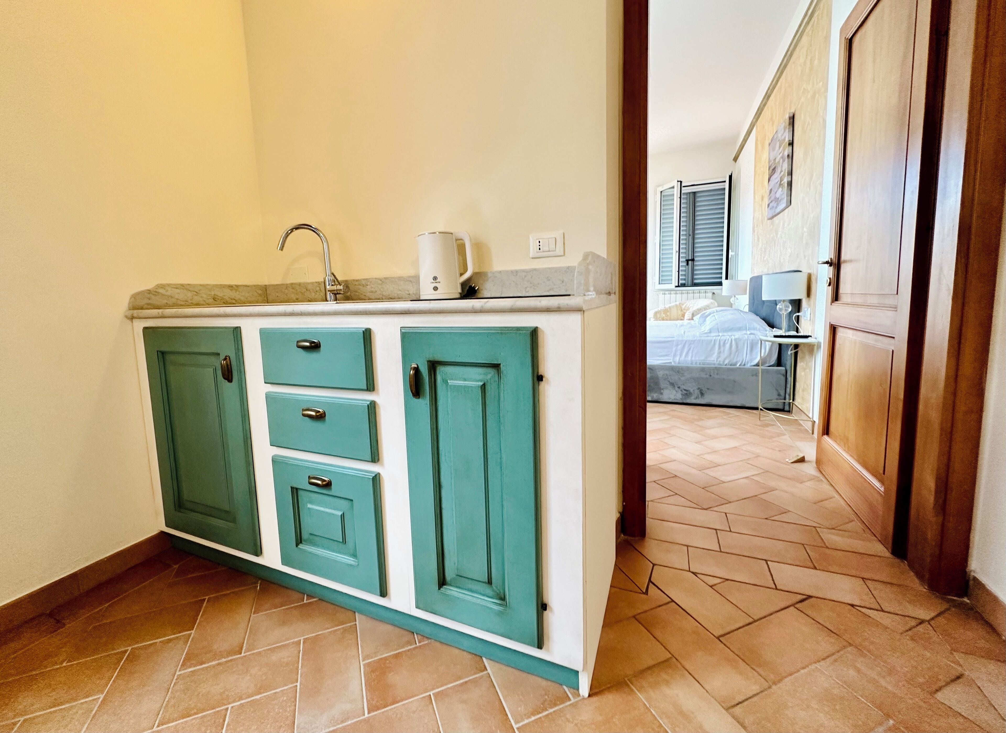 A compact kitchen with teal cabinets, a sink, and a countertop.