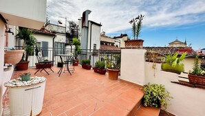 Une terrasse sur le toit, agrémentée de plantes en pot, d’une table et de chaises.