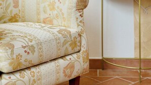 Un canapé à motifs floraux, une lampe posée sur une table blanche et un sol carrelé.