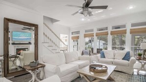 A spacious living room with white sofas, a wooden coffee table, and a ceiling fan. - 4 Bikes - Walk to beach, 2 Pools - `Gulf Station` (Santa Rosa Beach)