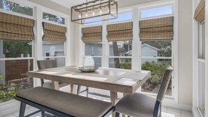 A dining area with a table and chairs, large windows with blinds, and a hanging light fixture. - 4 Bikes - Walk to beach, 2 Pools - `Gulf Station` (Santa Rosa Beach)
