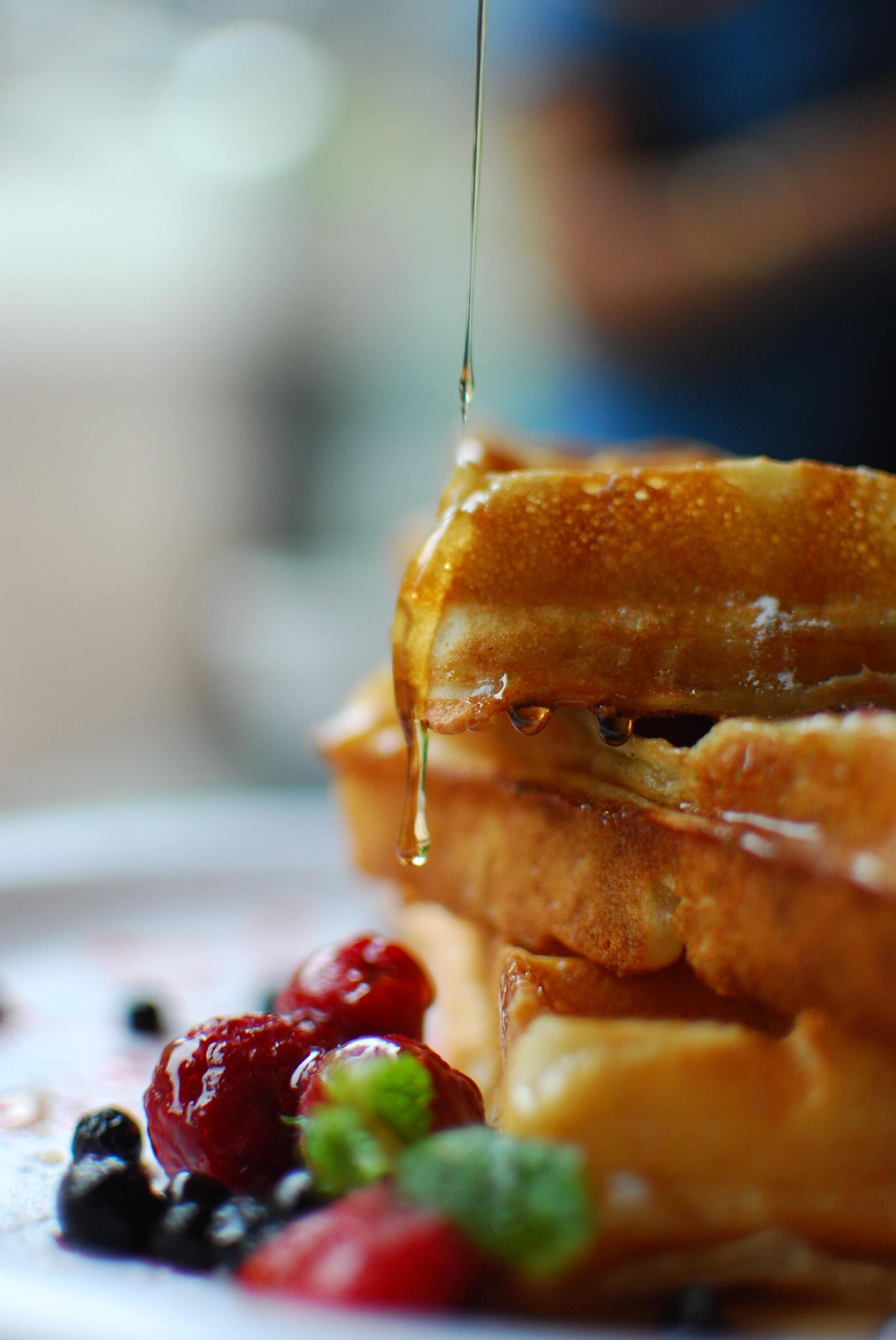 A close-up of a breakfast plate with French toast, syrup, and berries.