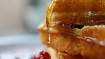 A close-up of a breakfast plate with French toast, syrup, and berries.