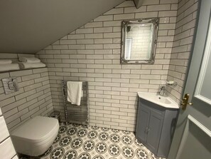 A bathroom with white subway tiles, a toilet, a sink, and a towel rack.