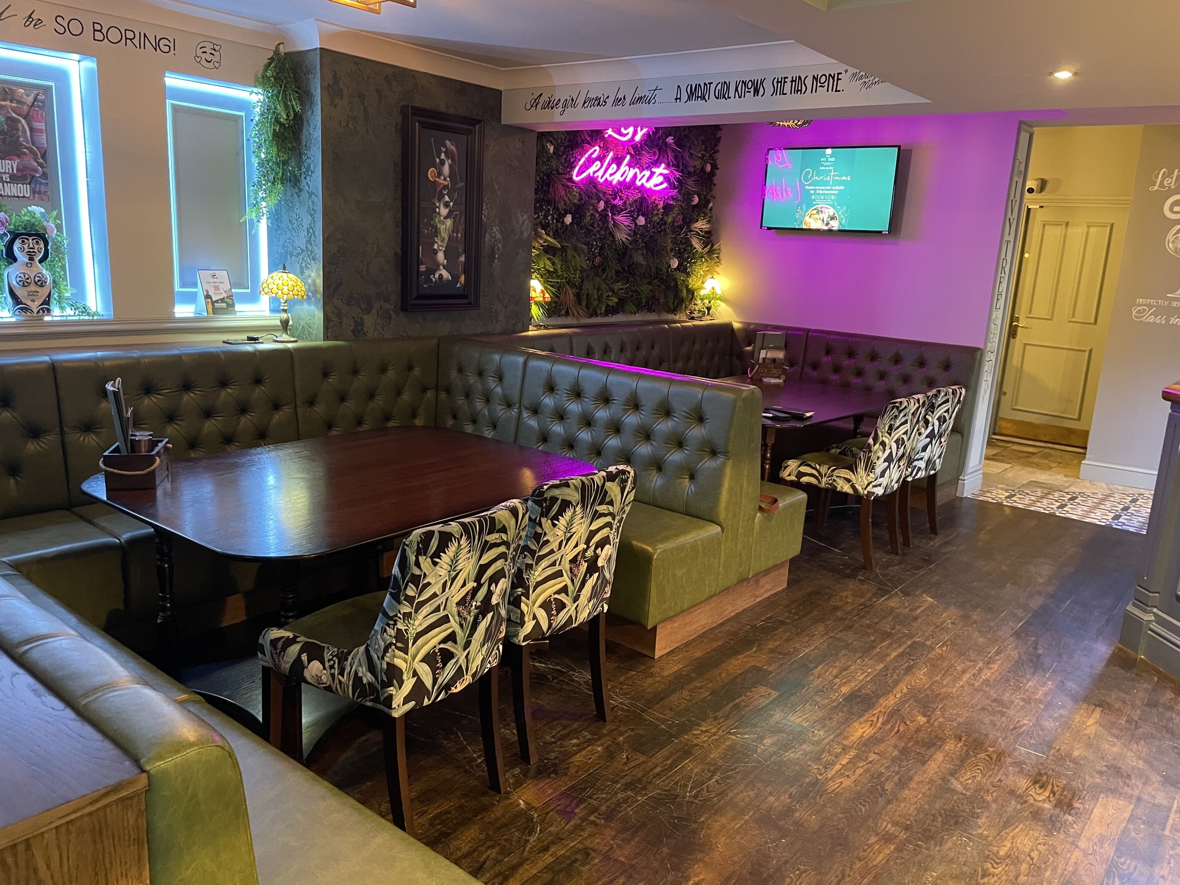Un restaurant chaleureux avec des tables en bois et des banquettes recouvertes d’un tissu vert.