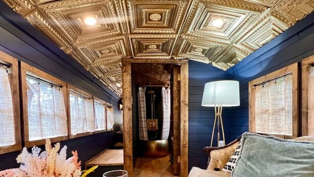 A room with a wooden floor, a sofa, a wooden coffee table with wine glasses, and a lamp. - The Hotel Avondale: 7b - 4bath + Skoolie tiny home (Birmingham)