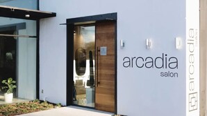 A modern building with a glass entrance and a wooden door. The exterior has a sign that reads "arcadia salon." - The Hotel Avondale: 7b - 4bath + Skoolie tiny home (Birmingham)