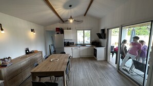 Une cuisine moderne avec une table à manger en bois, des meubles blancs et une grande fenêtre donnant sur un jardin.