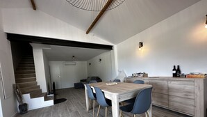 Une cuisine moderne avec une table et des chaises en bois, un escalier menant à une autre pièce et un luminaire fixé au mur.
