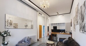 A modern living room with a sofa, a coffee table, and a dining area with a kitchen in the background. - Lovely 2-bed Apartment in Canterbury (Canterbury)