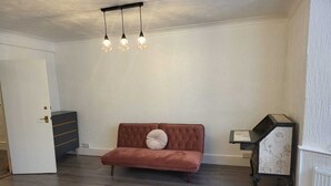 Ein Zimmer mit einer braunen Couch, einem kleinen Beistelltisch und einer Pendelleuchte.