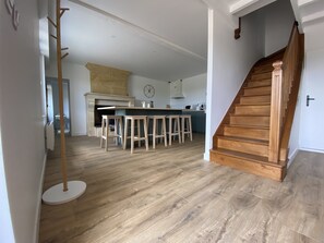 Een moderne keuken met een centraal eiland, houten vloeren en een trap naar een hoger niveau.