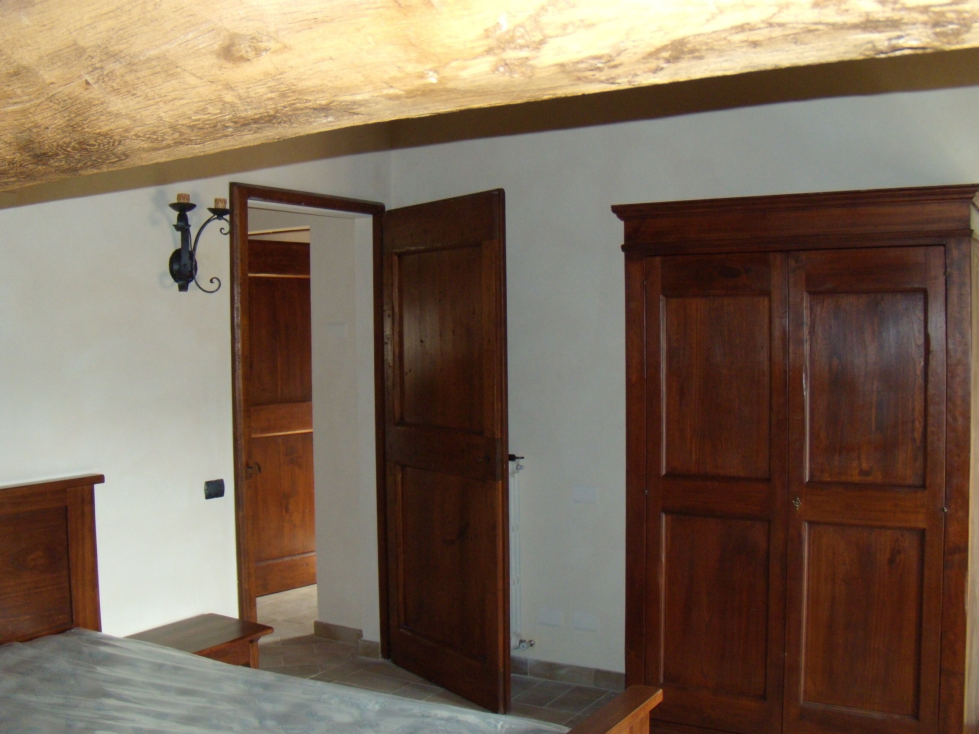 Une chambre à coucher avec une armoire en bois, une table de chevet et une commode avec un miroir.