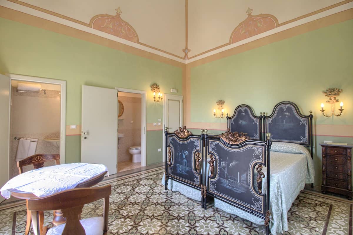 Een slaapkamer met een bed, nachtkastje, stoel en een tafel.