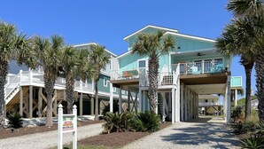 Un edificio affacciato sulla costa con diverse terrazze e balconi, circondato da palme.