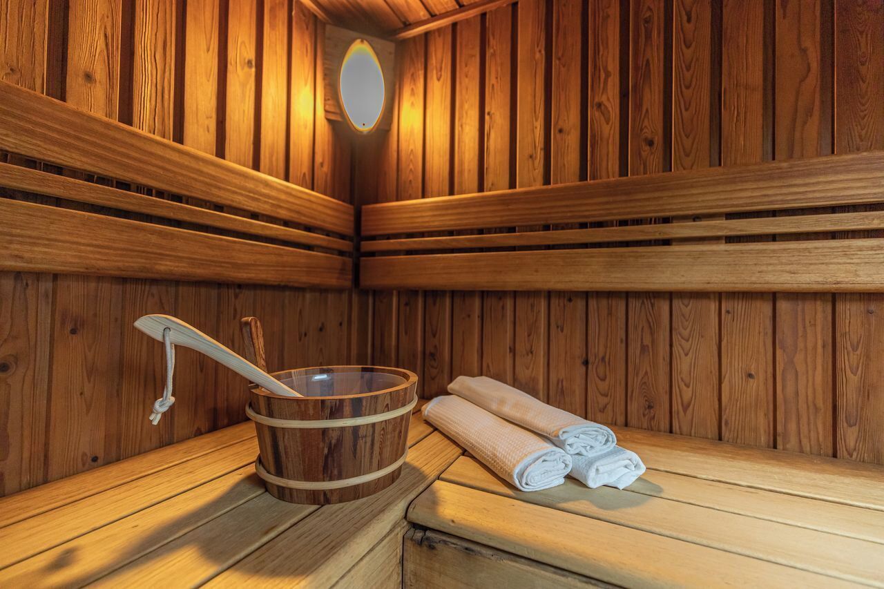 Una sauna de madera con bancos, un cubo de madera y toallas.