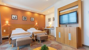 Una habitación de hotel con dos camas, un escritorio, un televisor y un armario.