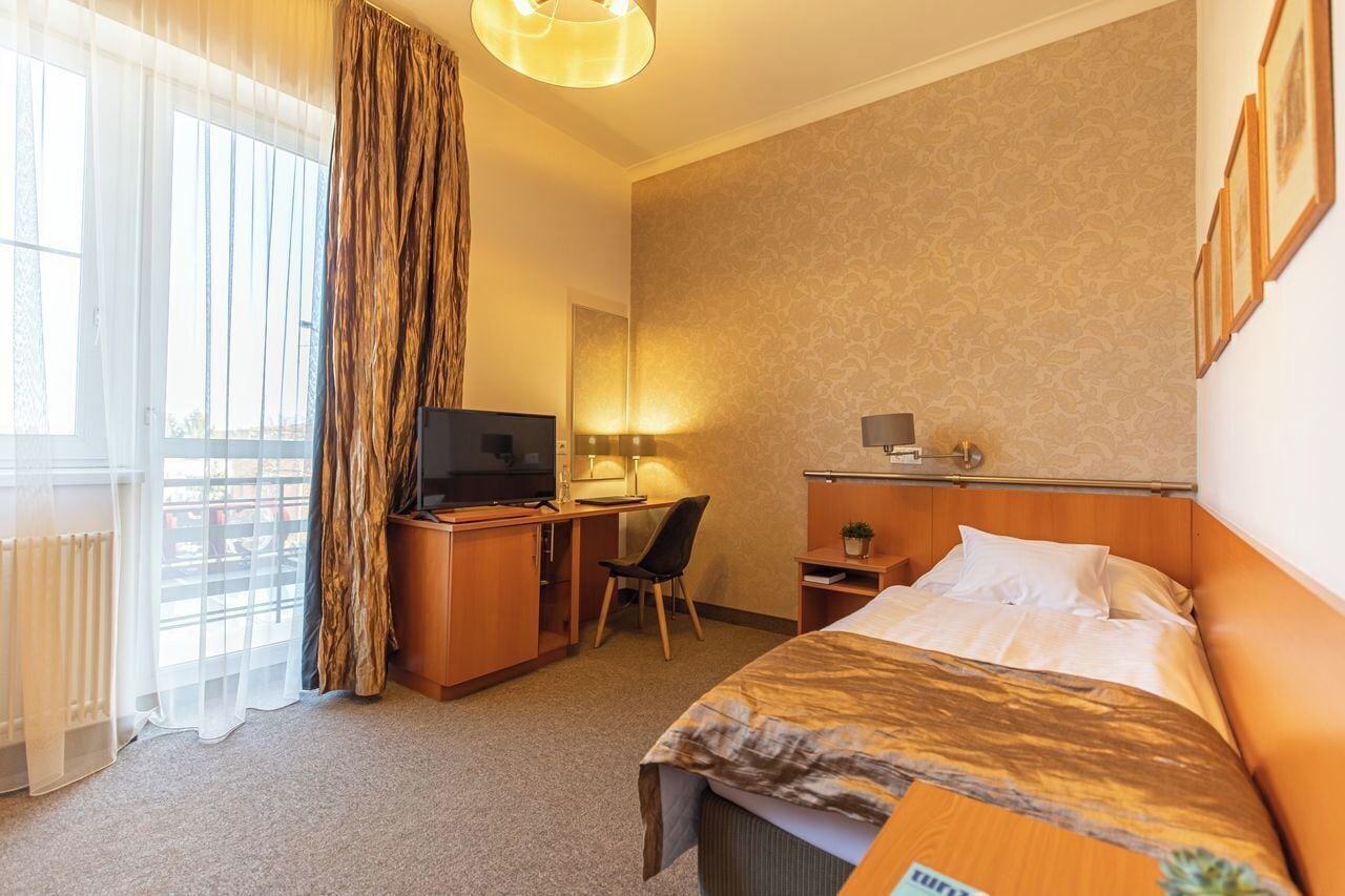 Ein Hotelzimmer mit Bett, Schreibtisch, Stuhl, Fernseher und Blick ins Freie.