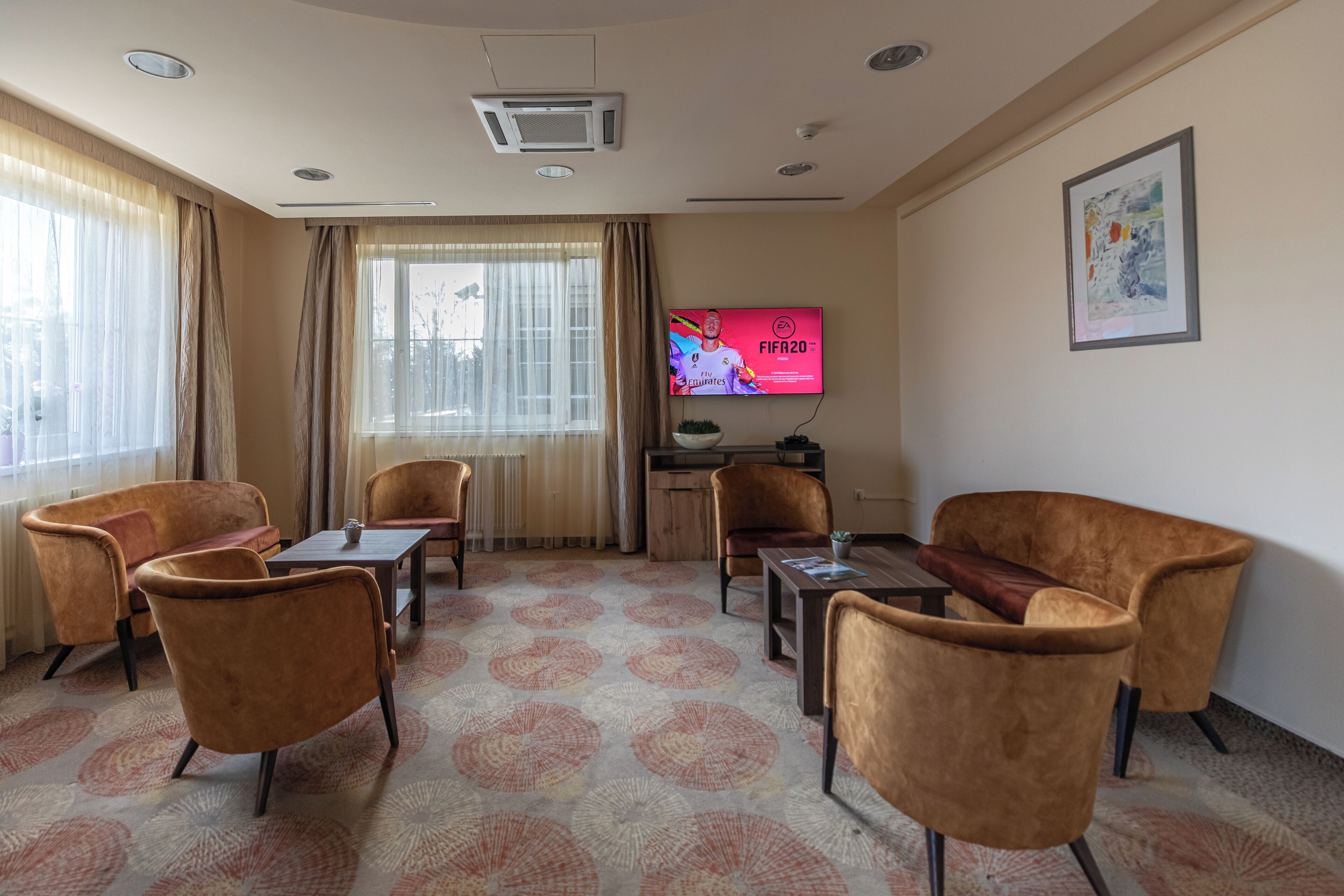 A hotel room with a large window, a flat-screen TV, a sofa, and a coffee table.