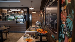 Zona de bufé con diferentes opciones de comida y un menú en una pizarra.