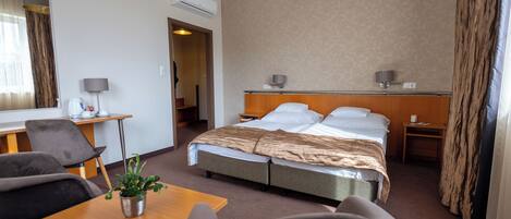 Una habitación de hotel con una cama, un escritorio, una silla, una lámpara y una planta en maceta.