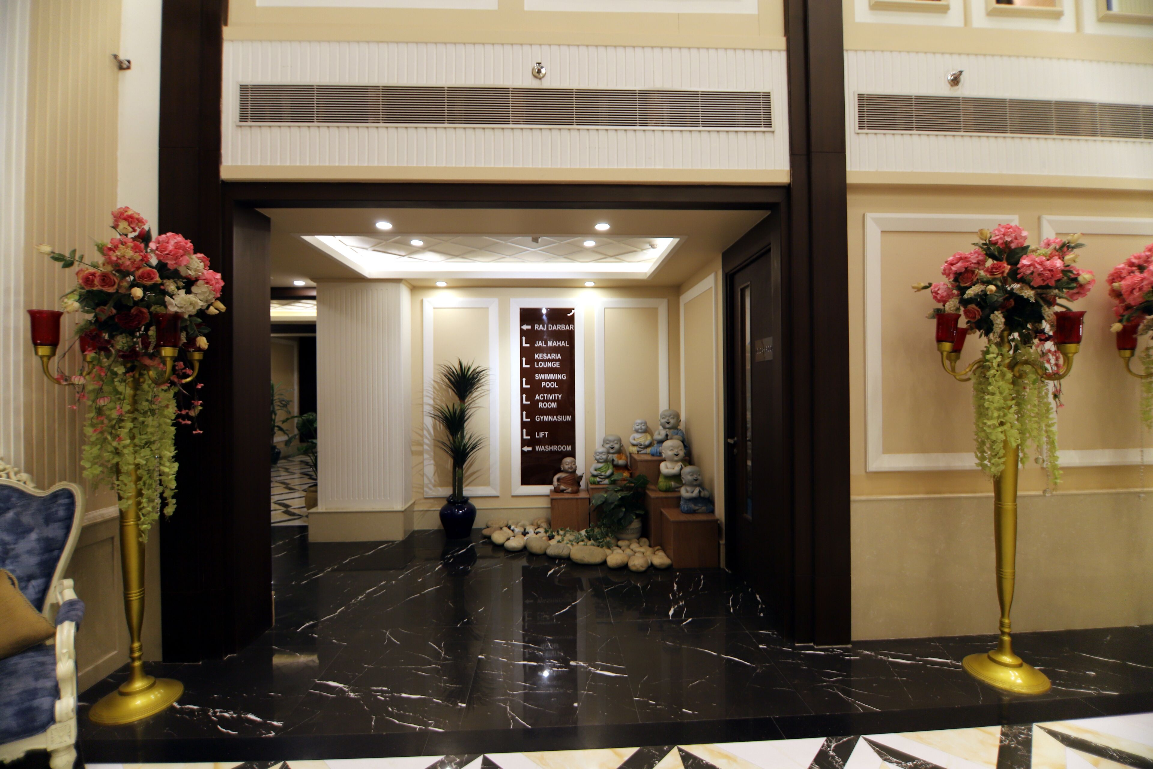 A lobby with a marble floor, a reception desk, and a wall-mounted information board listing hotel amenities.