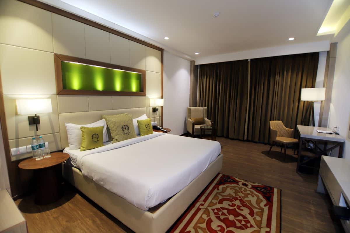 A hotel room with a large bed, bedside tables, a desk, and a chair.