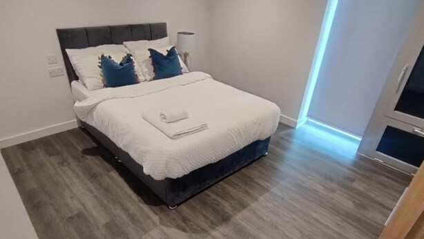 Een moderne slaapkamer met een bed, houten vloeren en een raam.