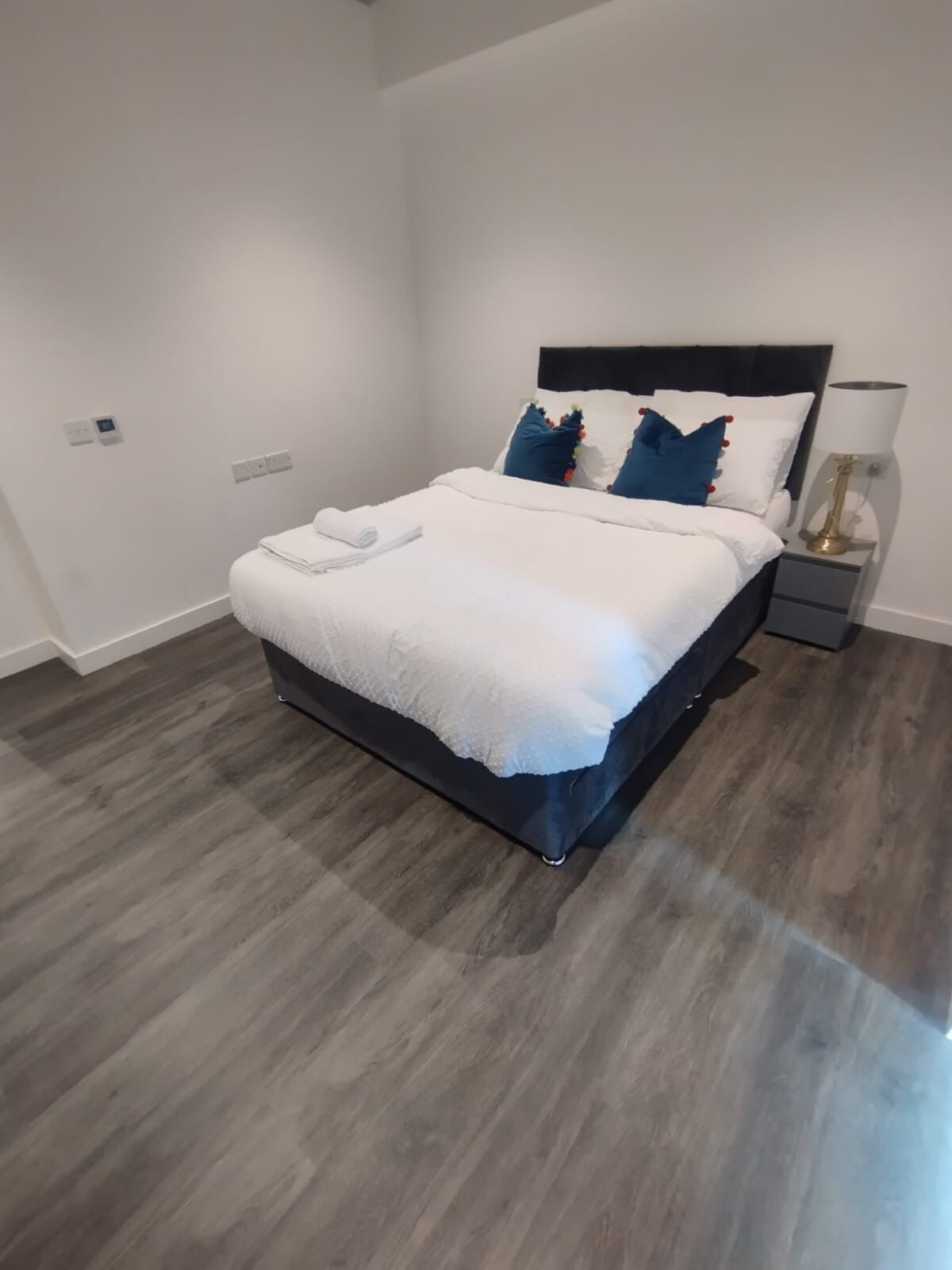 Une chambre à coucher moderne avec un lit, des tables de chevet et une lampe.