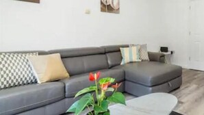 Een moderne woonkamer met een grijze modulaire bank, een marmeren salontafel en een potplant.