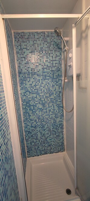 Een douche, handdoeken, zeep, toiletpapier